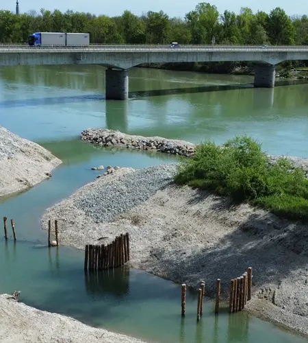 Luftaufnahme einer Brücke über einen Fluss mit klarem, grünem Wasser und Kiesbänken.